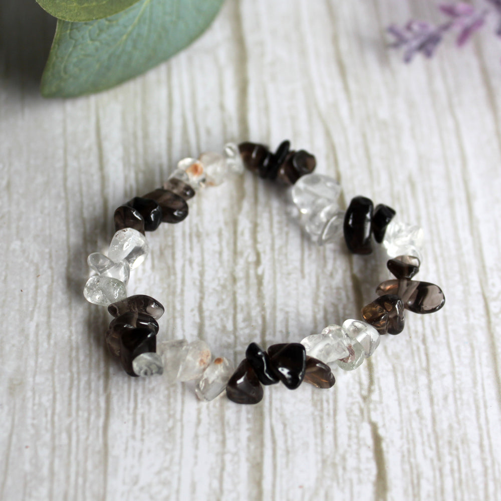 Smoky quartz and clear quartz stretch bracelet with natural black and clear gemstone chips on white background