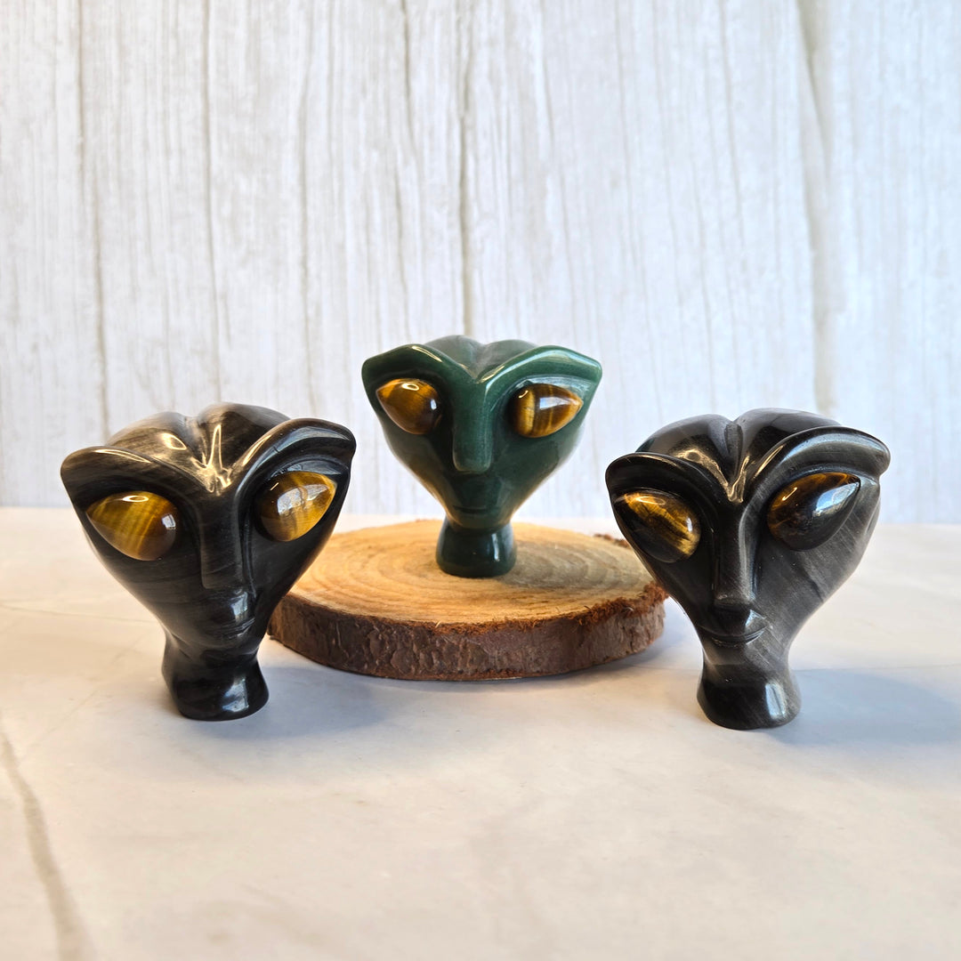 Green aventurine and silver sheen obsidian alien heads side by side showing crystal options