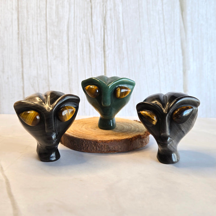 Green aventurine and silver sheen obsidian alien heads side by side showing crystal options