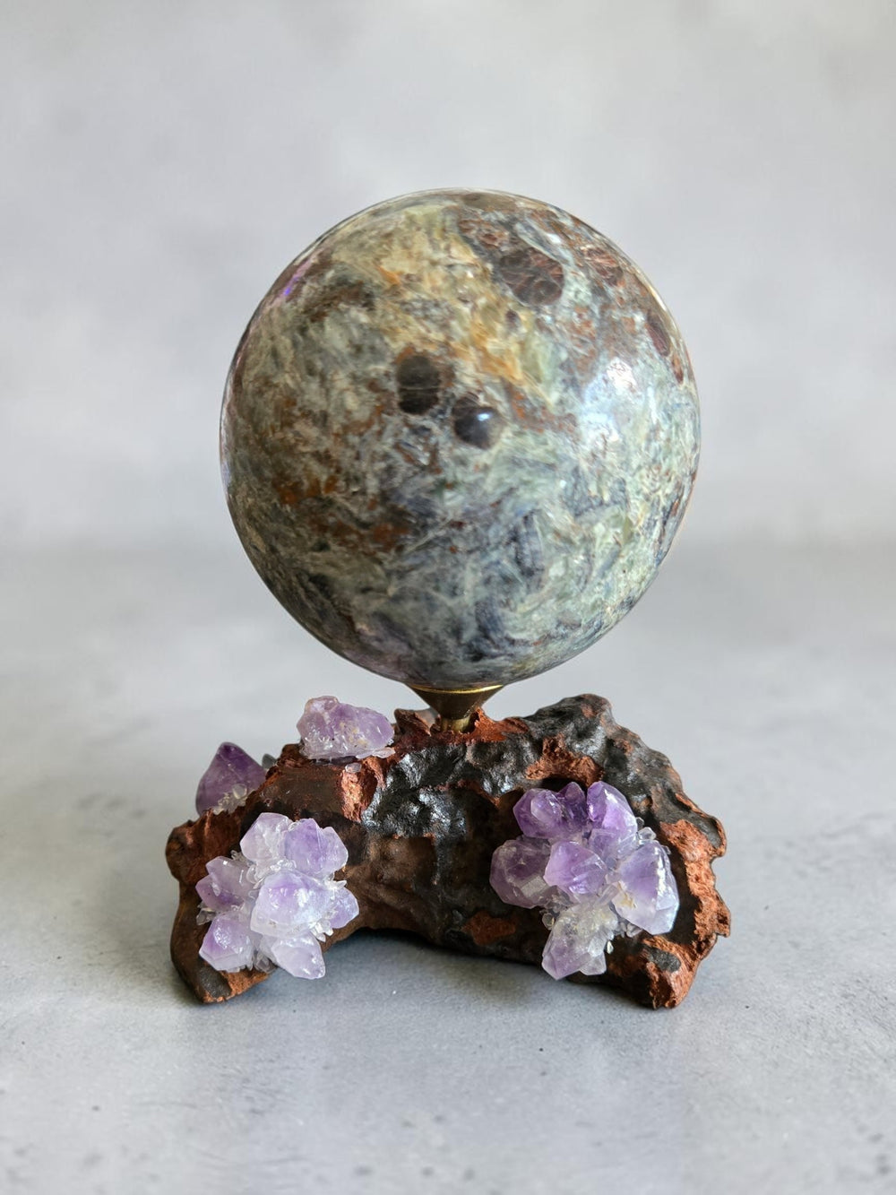 Amethyst driftwood crystal sphere stand displaying large gemstone sphere with purple amethyst clusters on natural wood base