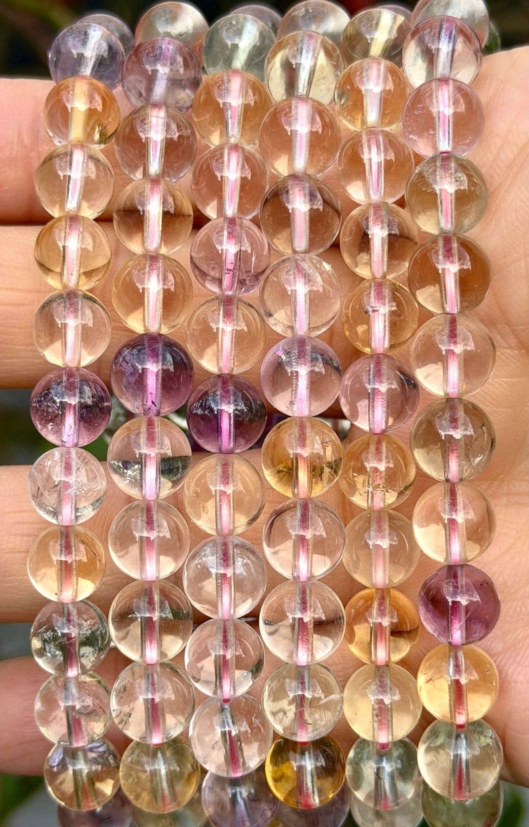 Close-up of natural Ametrine crystal bracelet beads showing translucent purple amethyst and golden citrine color zones in 8mm round stones