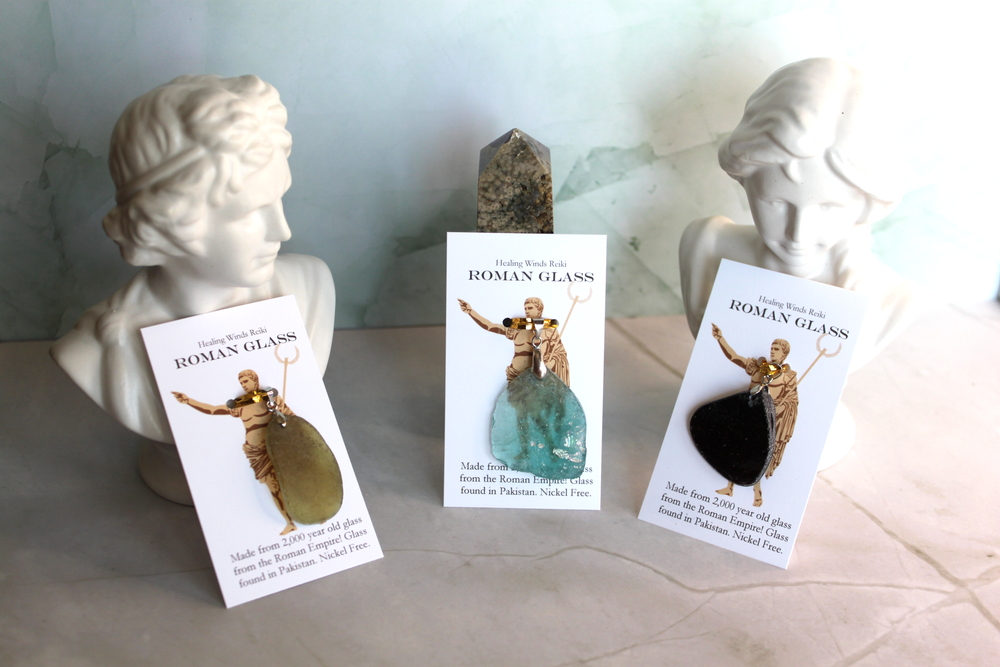 Collection of three authentic ancient Roman glass pendants showing natural color variations in blue and green