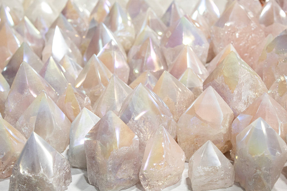 Collection of Angel Aura Rose Quartz polished tower points showing natural variation in pale pink and iridescent rainbow shimmer from platinum silver and gold bonding, sourced from Brazil