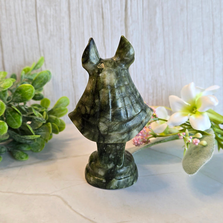 Back view of hand-carved Anubis serpentine statue showing natural green stone patterns