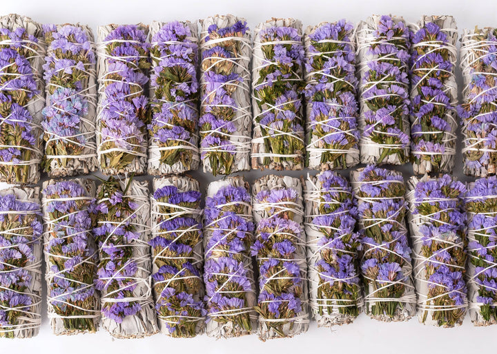 Hand-tied white sage smudge wand showing 100% cotton string binding and dried purple Statice