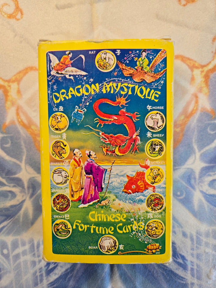 Close-up of Dragon Mystique Chinese Fortune Cards box cover featuring a red dragon, Chinese zodiac animals, and two sages — 1976 vintage collectible from Hong Kong