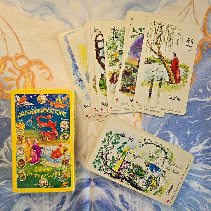 Dragon Mystique Chinese Fortune Cards 1976 box with theme cards fanned out showing Desire, Search, Career, Negotiation, and Wealth cards — vintage Hong Kong divination deck