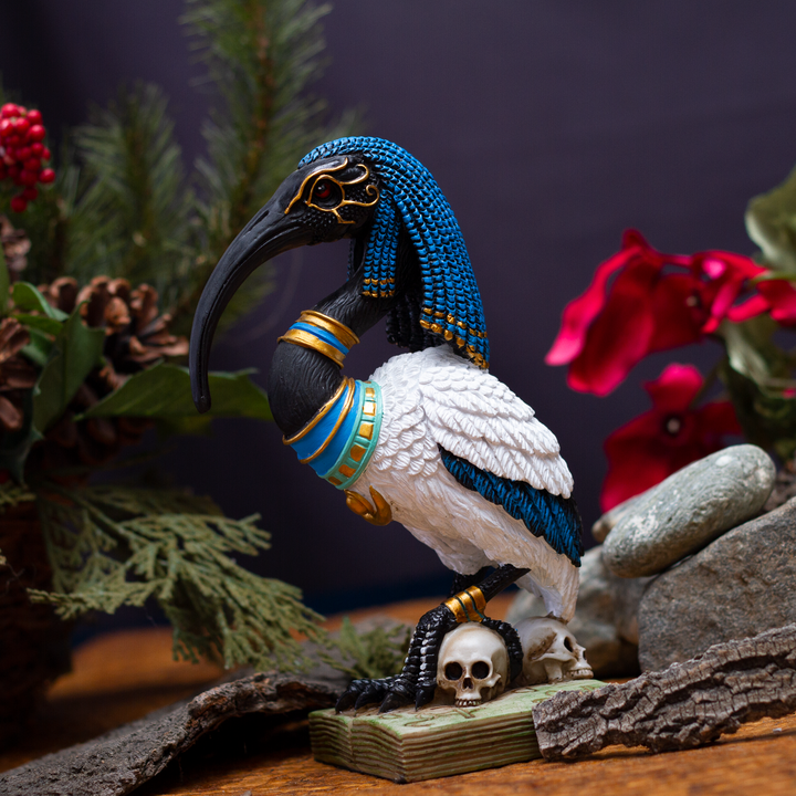 Egyptian Thoth figurine styled on an altar or sacred space setting with plants and wood