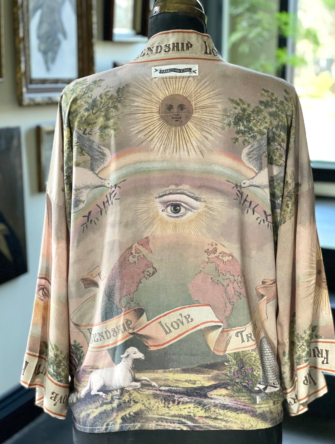 Close-up of historic lithograph symbols on the Friendship Love and Truth kimono — beehive, dove, sun, and clasped hands