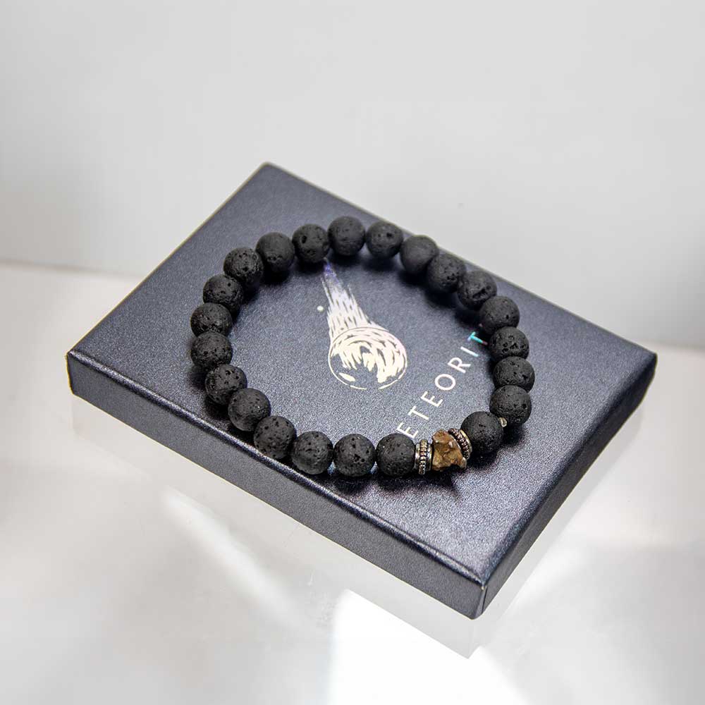 Genuine meteorite lava stone bracelet resting on black meteorite gift box with raw meteorite focal bead visible