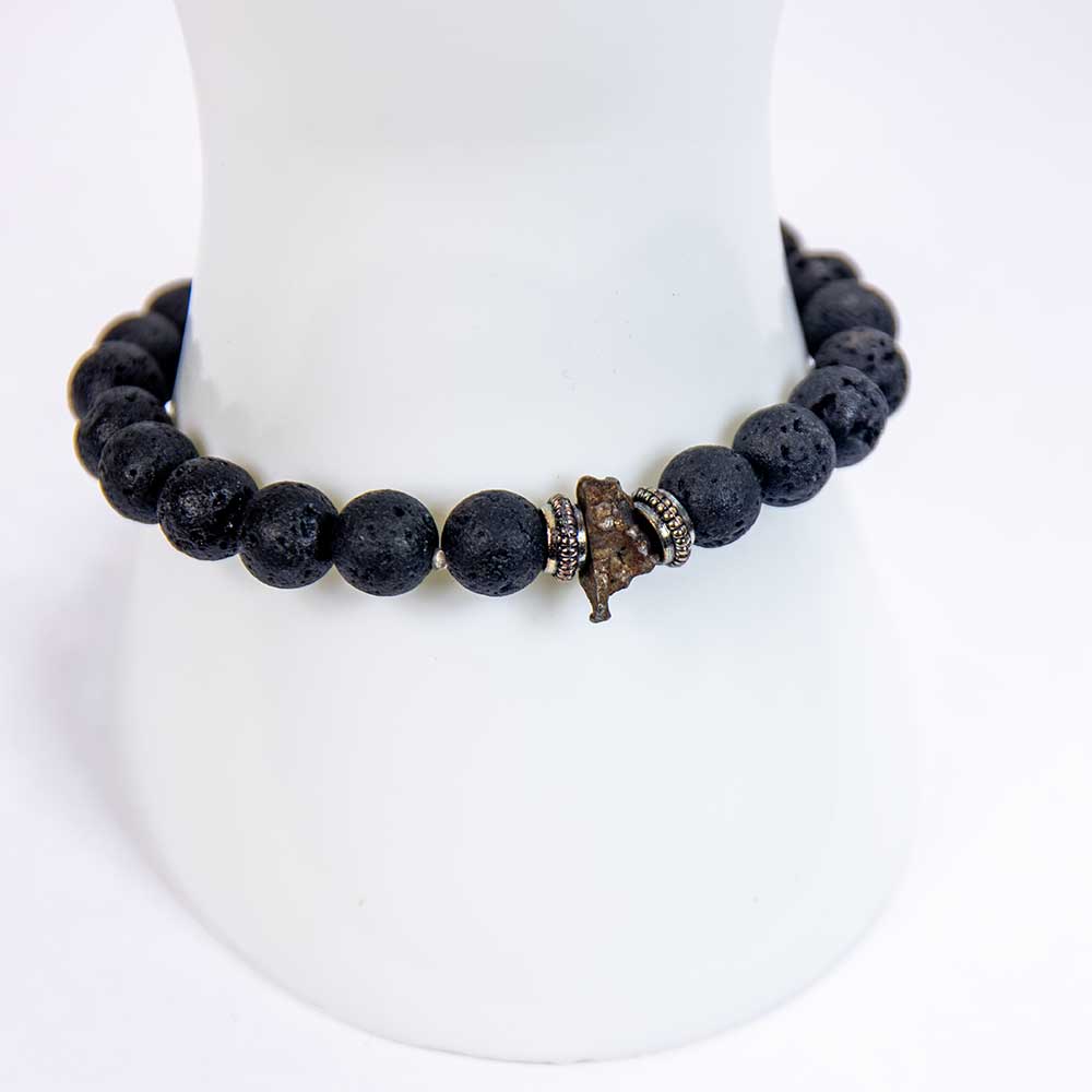 Genuine meteorite bead lava stone stretch bracelet on white display stand showing raw meteorite focal bead and silver spacers