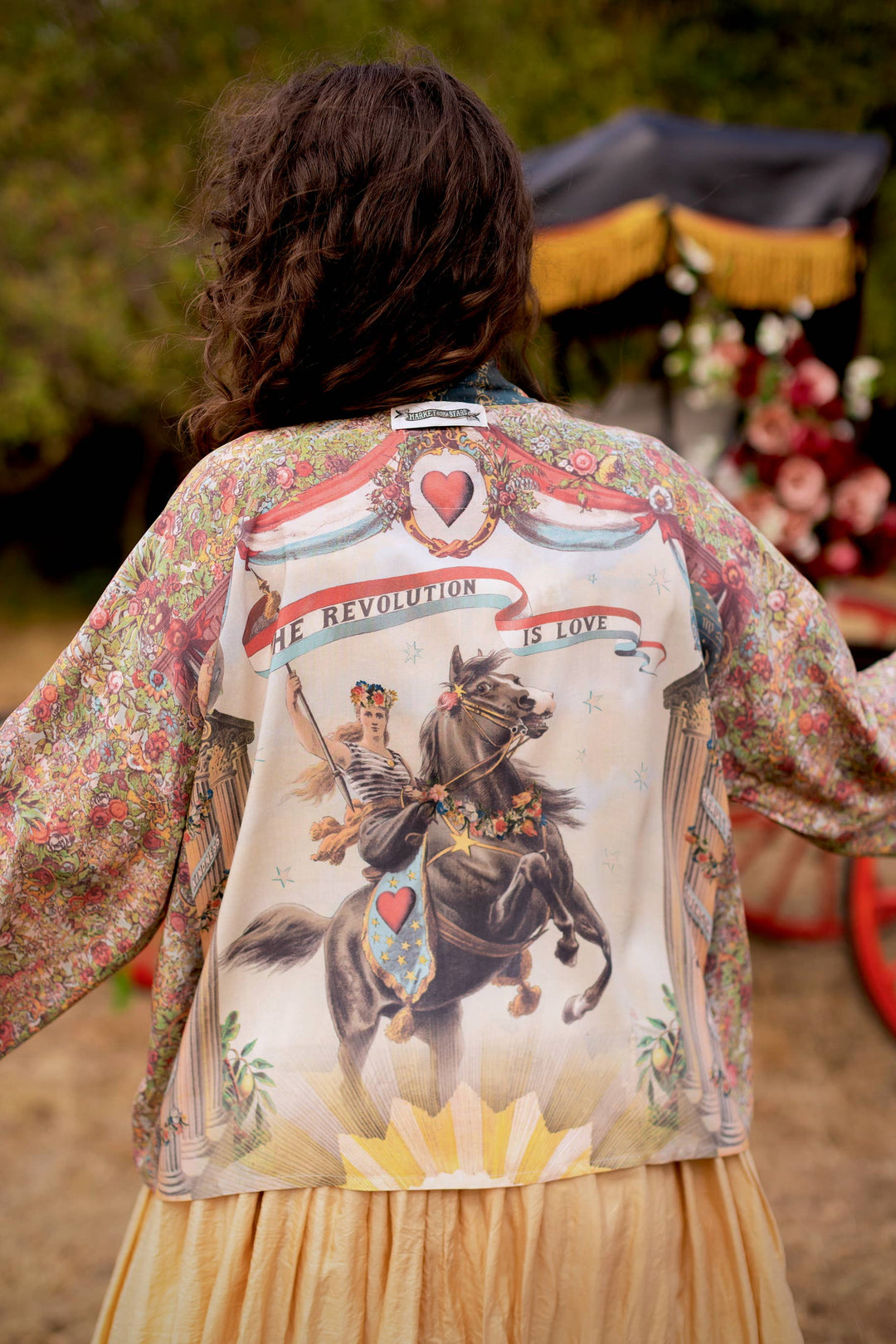 Close-up of 1892 woman on horseback print on Market of Stars Love Revolution crop kimono, showing vintage floral and rosette details in sun-washed blue and aged ivory