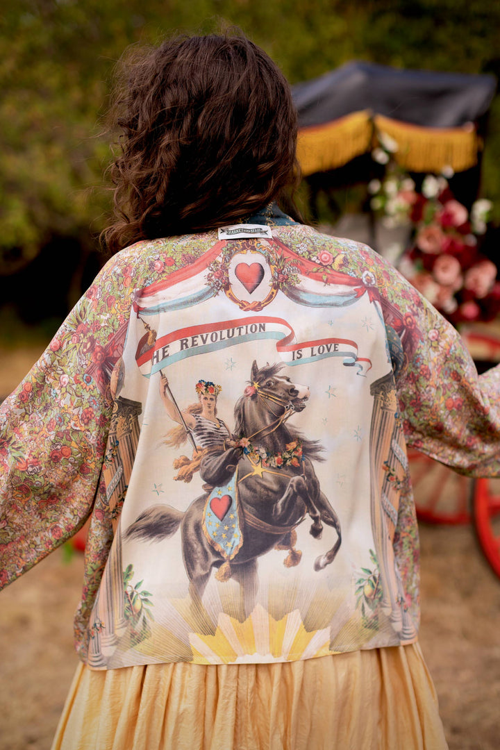 Close-up of 1892 woman on horseback print on Market of Stars Love Revolution crop kimono, showing vintage floral and rosette details in sun-washed blue and aged ivory