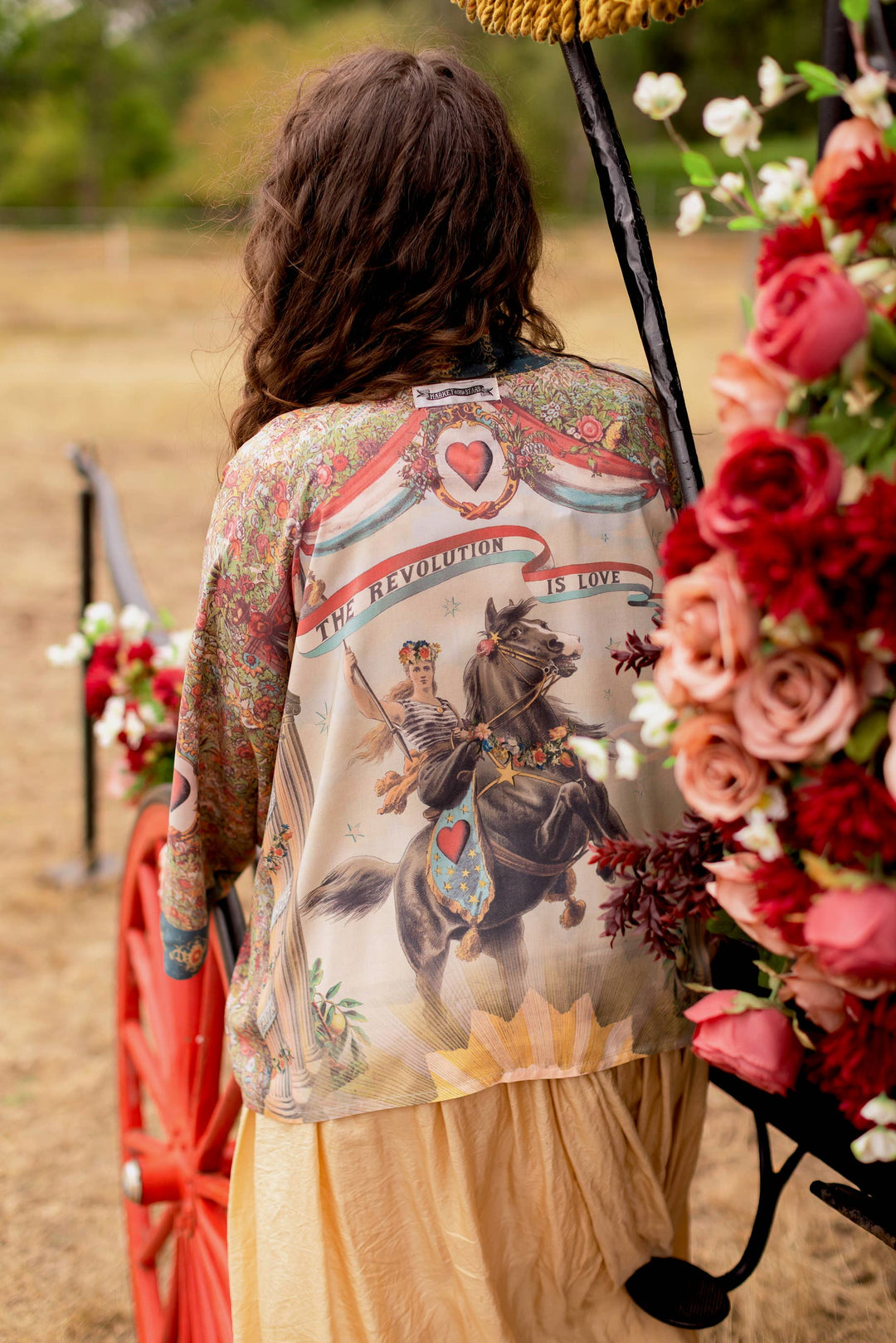 Back view of Market of Stars Love Revolution crop kimono featuring 1892 woman on horseback print with "Revolution is Love" banner, vintage florals in faded red and ivory