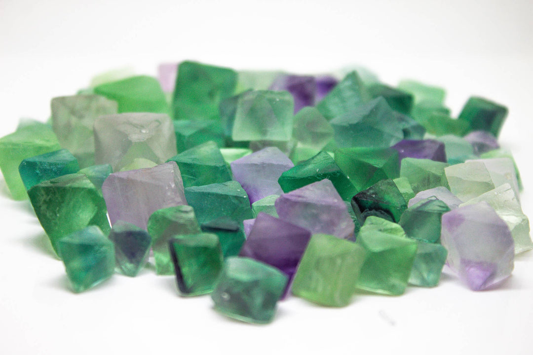 Close-up angled view of natural rainbow fluorite octahedrons showing translucent green and purple faceted crystal geometry