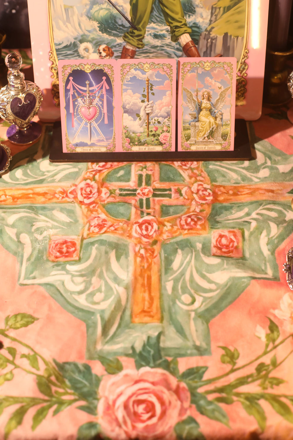 Renaissance Fantasy Tarot Cloth Rose Cross styled as altar reading mat with tarot cards displayed on stand, crystal bottles, and rose cross center motif in blush pink and sage green