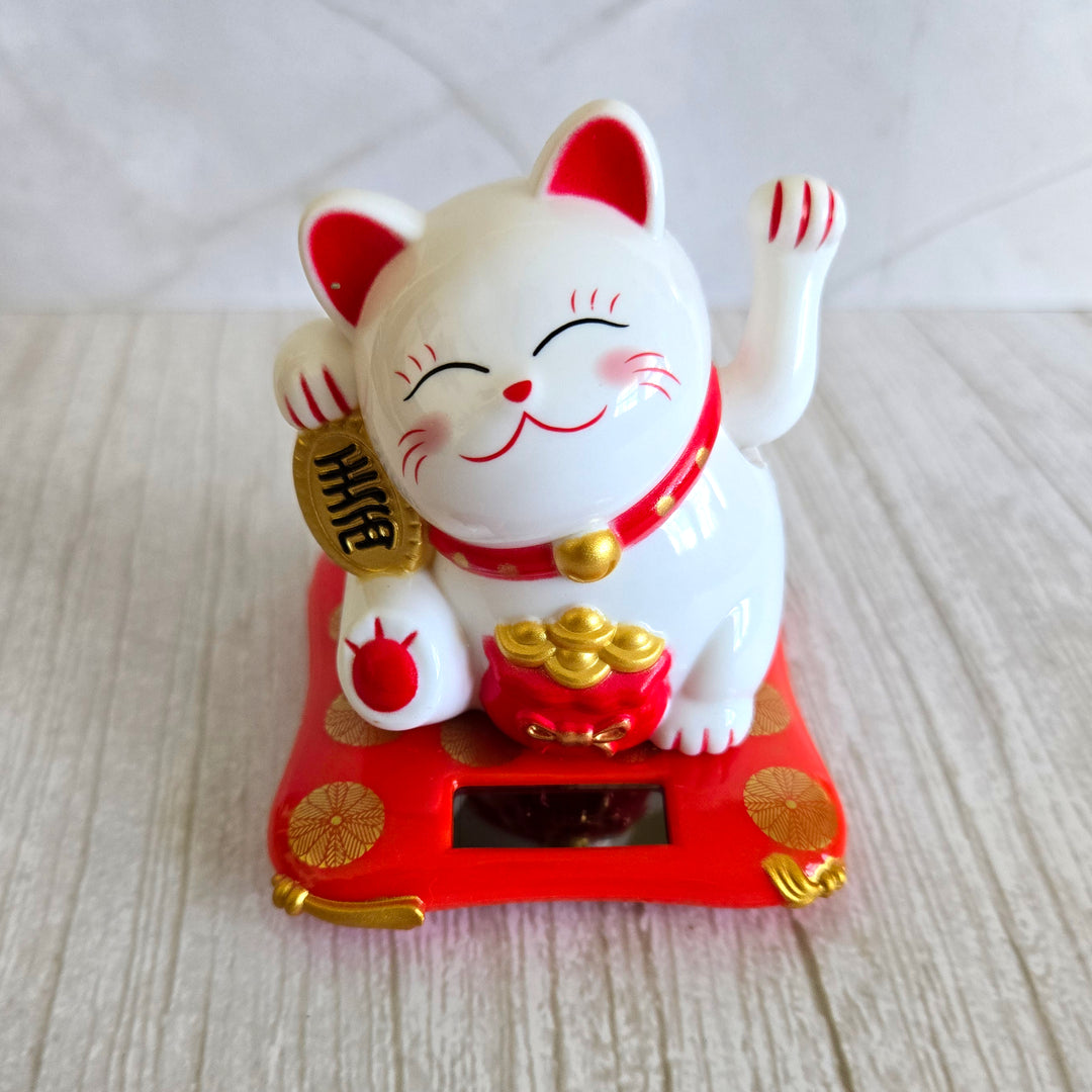 White solar powered Maneki-Neko lucky cat with waving left paw on red base front view