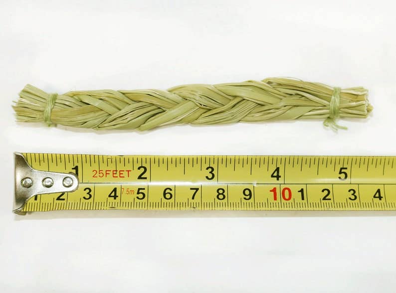 Single sweetgrass braid beside a measuring tape showing its approximate length.