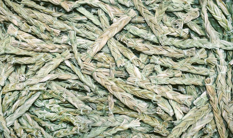 Close-up of overlapping sweetgrass braids showing their woven texture and natural color variations.