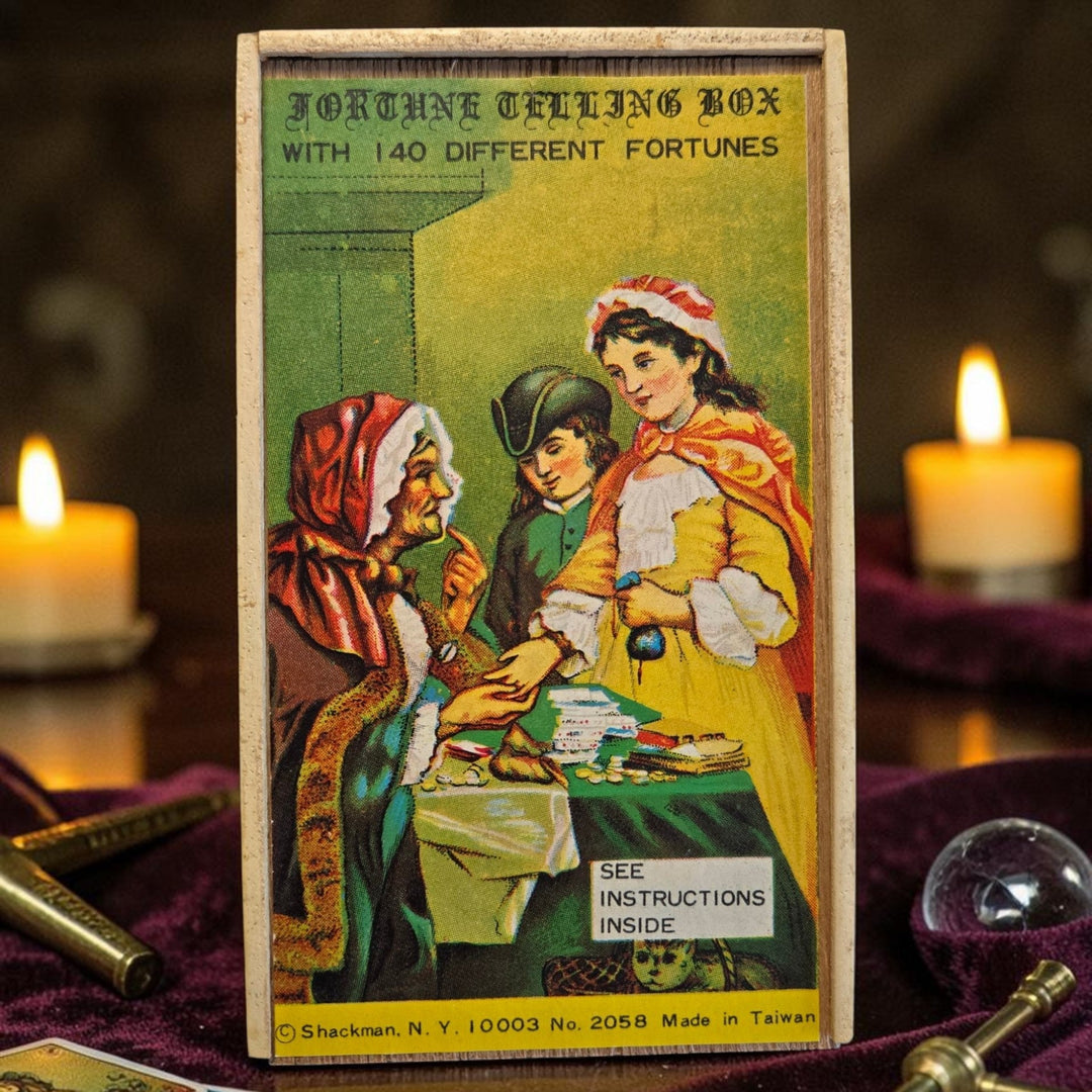 Close-up of vintage Shackman Fortune Telling Box lid with Victorian fortune teller illustration, styled with candles and crystal ball on purple velvet