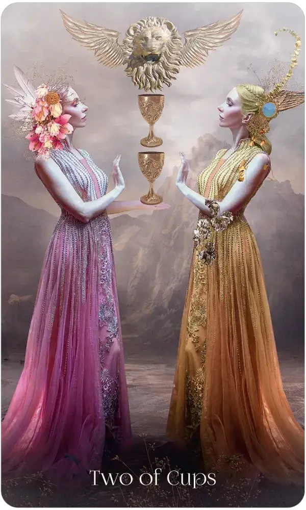When Women Had Wings Tarot — Two of Cups card featuring two ethereal women in pink and gold gowns facing each other with two golden chalices and a winged lion above